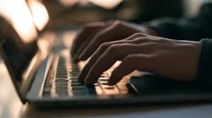 Hands typing on a laptop keyboard in a classroom - joining and logging in to Blooket